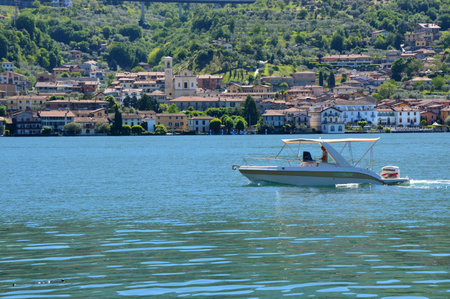 LAKE ISEO, ITALY - MAY 13, 2017: Speedboat crosses Lake Iseo view from ferry with Monte Isola on the background. Italian landscape. Island on lake.のeditorial素材