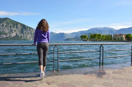 Beautiful girl looking at lake and mountains sunny landscape on outdoor background. Travel healthy lifestyle concept.の写真素材