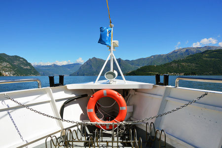 LAKE ISEO, ITALY - MAY 13, 2017: view of bow ferry with flag and the island Monte Isola on the background. Italian landscape. Island on lake.のeditorial素材