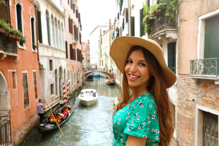 Smiling cheerful woman with hat and green dress in her venetian holidays. Happy attractive girl at camera in Venice, Italy.の写真素材