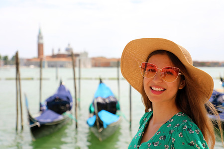 Smiling woman with sunglasses and hat looking at camera with Venice Lagoon on the backgroundの写真素材