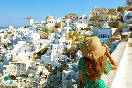 Santorini woman enjoying panoramic view of Oia village from Santorini, Cyclades, Greeceの写真素材