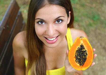 Close up of brazilian woman showing papaya healthy fruit outdoor.の写真素材