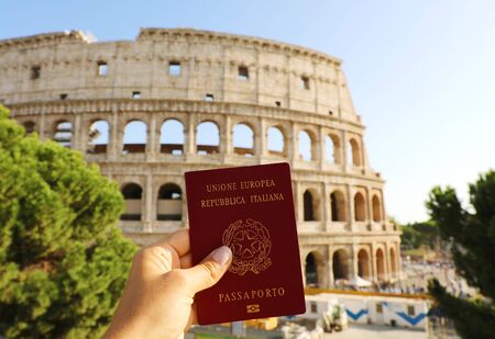 Citizenship concept: hand hold Italian passport in front of Colosseum in Rome.の写真素材