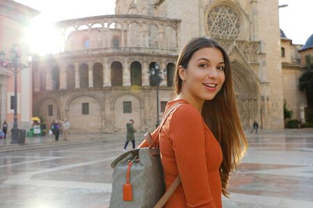 Portrait of beautiful tourist woman in Valencia with Cathedral on the background. Smiling traveler girl with Valencia landmark in Spain.の写真素材