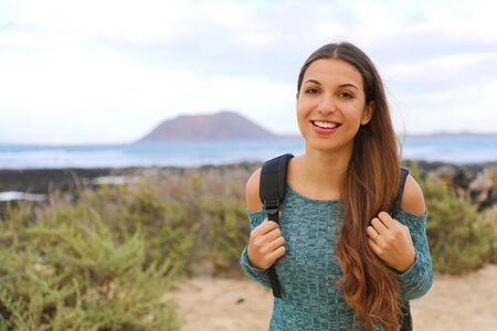 Smiling young female backpacker hiking in Fuerteventura Island, Spain