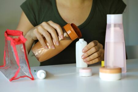 Travel kit for transporting cosmetics on airplane. Woman poured cosmetics liquid into small bottles...