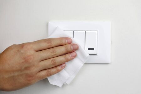 COVID-19 Pandemic Coronavirus Woman Hand Disinfect Light Switches with Wet Wipes Alcohol Cleaning Against Coronavirus Disease 2019 Outbreak Contamination Preventionの写真素材