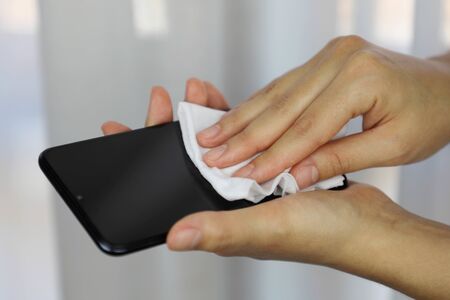 COVID-19 Pandemic Coronavirus Woman Cleaning with Wet Wipes Smart Phone Screen Disinfect Against Coronavirus Disease 2019 Outbreak Contamination Preventionの写真素材