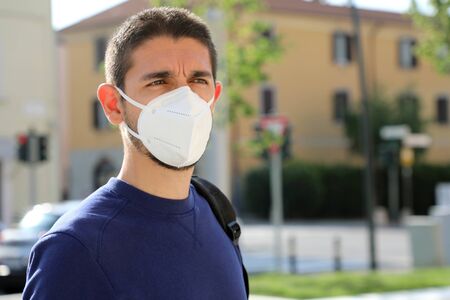 COVID-19 Pandemic Coronavirus Man in city street wearing KN95 FFP2 face mask protective for spreading of Coronavirus Disease 2019. Portrait of man with face mask against SARS-CoV-2.の写真素材