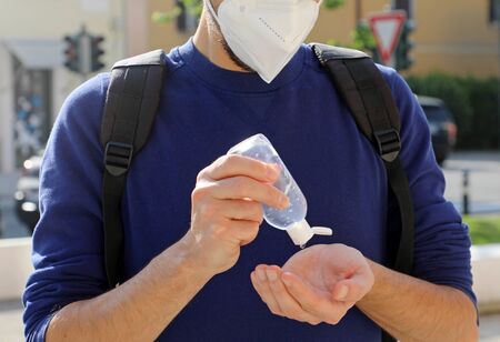 COVID-19 Pandemic Coronavirus Close up Unidentified Man with KN95 FFP2 Mask using Alcohol Gel Sanitizer Hands in City Street. Antiseptic, Hygiene and Healthcare concept. Focus on hands.の写真素材