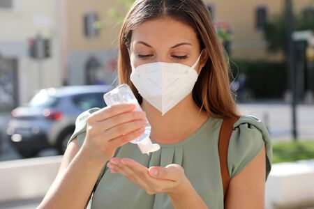 COVID-19 Pandemic Coronavirus Close up Woman with KN95 FFP2 Mask using Alcohol Gel Sanitizer Hands in City Street. Antiseptic, Hygiene and Healthcare concept.の写真素材