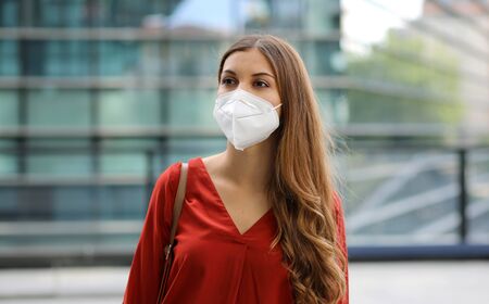 Sense of bewilderment. Young woman in empty city street wearing protective mask. Girl with face mask feeling alone during a pandemic.の写真素材