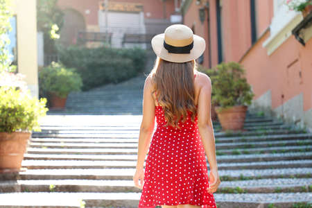 Travel in Italy. Back view of tourist girl climbs the stairs in Bellagio, Italy. Young traveler woman on her summer vacations on Lake Como, Southern Europe.の写真素材