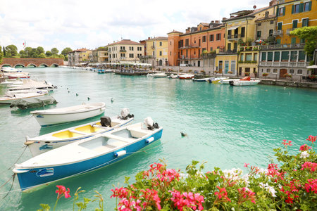 PESCHIERA DEL GARDA, ITALY - JUNE 19, 2020: Peschiera del Garda colorful and flowered harbor with boats moored Lake Garda, Italyのeditorial素材