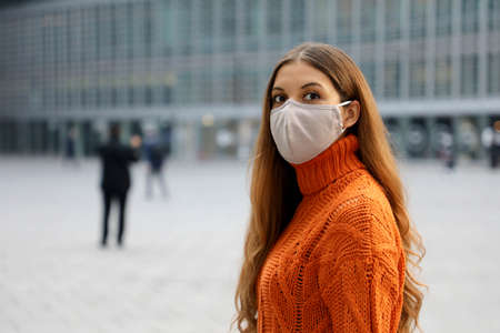 Portrait of a young business woman wearing protective mask standing on the street looking in front of her worried. Copy space.の写真素材