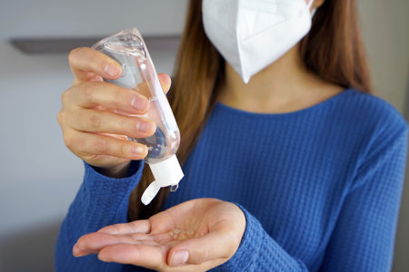 Close up woman hands using alcohol gel sanitizer wearing FFP2 KN95 face mask Antiseptic, hygiene and healthcare concept.の写真素材