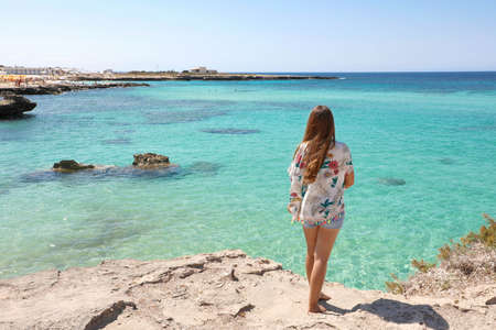 Longing for summer, longing for holidays. Back view on female tourist enjoying view crystalline water of the ocean.の写真素材