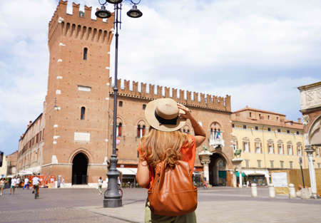 Cultural tourism in Italy. Rear view of female backpacker visiting old medieval town of Ferrara,...