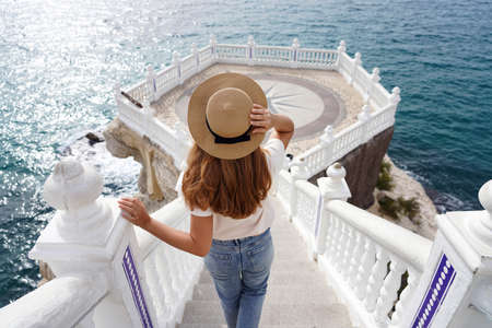 Holiday in Spain. Back view of young traveler woman descends stairs towards the Mediterranean Balcony in Benidorm, Alicante, Spain.の写真素材
