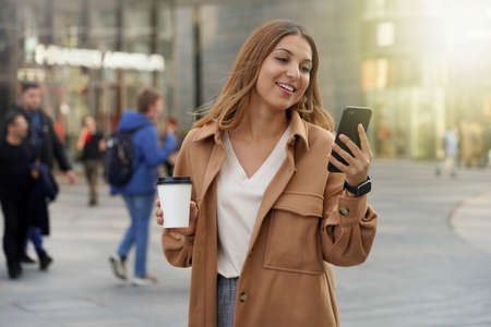 Young business people. Smartphone using. Take away coffee. Smart watch. Black friday shopping. Christmas. Blurred people background.の写真素材