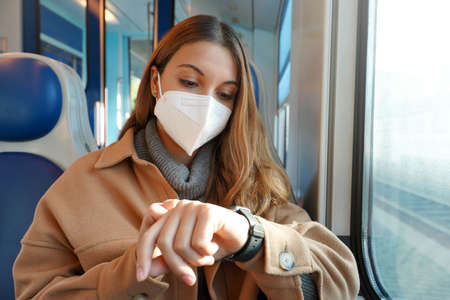 Public transport late. Business woman on train looking at smartwatch while her train is stopped on railroad in the middle of nowhere. People and the delay with transportation.の写真素材