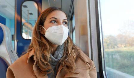 Travel safely on public transport. Panoramic banner of beautiful woman wearing FFP2 KN95 face mask on train looking through the window.の写真素材