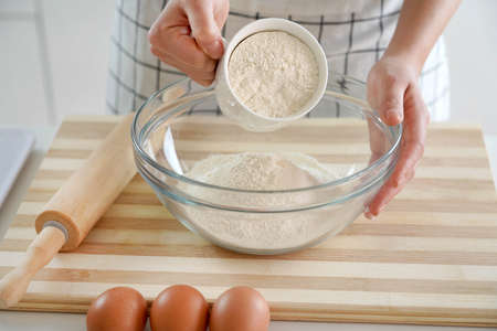 Close-up of woman hands pouring the flour into the bowl. Increasing price of wheat, flour and bread....