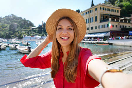 Portofino tourist girl taking selfie photo on famous luxury destination. European tourism attraction in Italy. Young woman on vacation.の写真素材