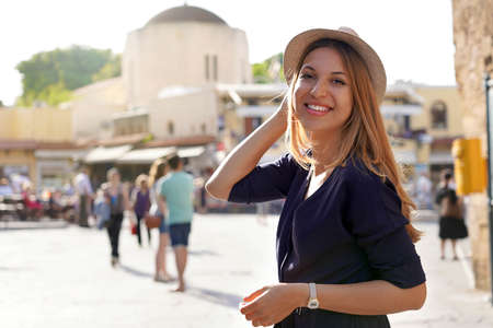 Smiling tourist girl visiting Ippokratous square in Rhodes city, Greece. Looks at camera.