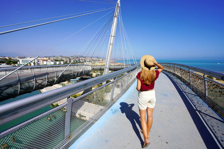 Young woman walking on Pescara modern bridge enjoying seascape from promenade in Abruzzo region, Italyの写真素材