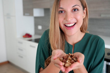 Beautiful healthy woman showing mix of nuts seeds dried fruit at the cameraの写真素材