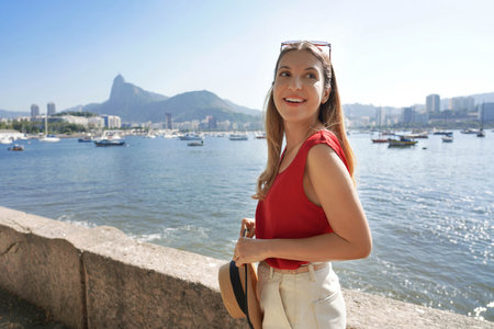Portrait of stylish tourist girl on famous Mureta da Urca short wall along Rio de Janeiro promenade with Corcovado mountain on the background in Rio de Janeiro, Brazilの写真素材