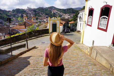 Holidays in Ouro Preto, Brazil. Back view of traveler woman descends street in the historic city of Ouro Preto, Minas Gerais, Brazil.の写真素材
