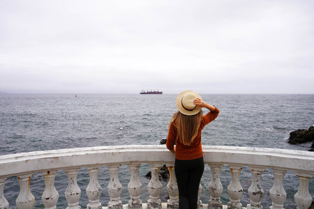 Back view of young woman looking Pacific Ocean from southern Americaの写真素材
