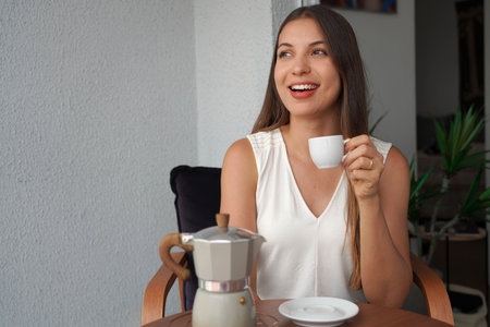 Attractive young woman sitting on terrace drinking Italian coffee espresso. Looking to the side.の写真素材