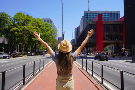 Tourist woman with open arms enjoying the view of Paulista Avenue in Sao Paulo, Brazilの写真素材