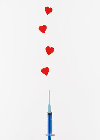 Creative symbol of safe worldwide vaccination. Syringe injecting hearts on white background, top viewの写真素材