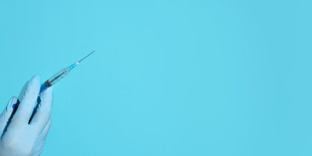Vaccination concept. Doctor's hand in medical gloves holding a syringe injection. Banner, copy space, top viewの写真素材