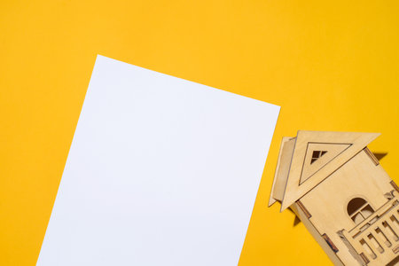Wooden house miniature and blank white paper mock up. top view, copy spaceの写真素材