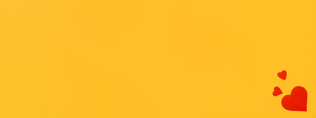 Three red cardboard hearts on a yellow background, flat lay. Banner, blank space for your messageの写真素材