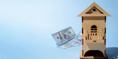 Model of wooden house and flying hundred dollar bills, banner copy space. The concept of buying (selling) housing, mortgage, apartment rentalの写真素材