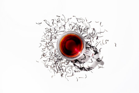 Glass cup of black tea and scattered dry ceylon tea leaves, top viewの写真素材