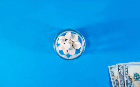 Money and a bottle with pills on a blue background, top view, copy space. Life insurance concept, pharmaceutical business, cost of drugs and treatment.の写真素材
