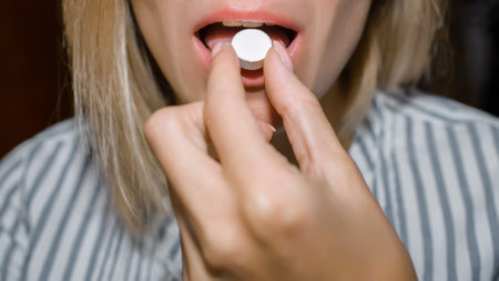 Woman puts the pill in her mouth. Young woman is taking medicine. croppedの写真素材