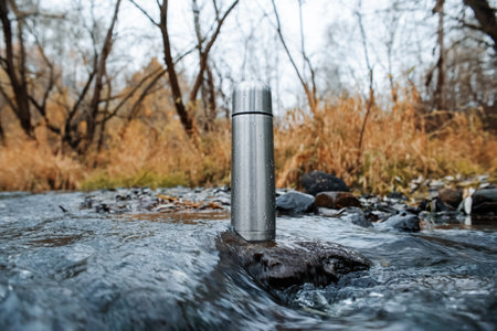 Steel vacuum flask, outdoor. A hiking flask is in the stream. Concept for outdoor activities, hot...