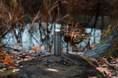 Traveling steel flask standing by the lake. autumn pond background. selective focus, blurの写真素材