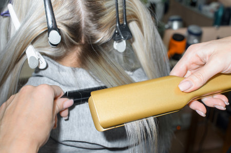 Keratin hair straightening with a professional iron. hair dresser performing hair treatment. Spa salon concept, hairdressingの写真素材