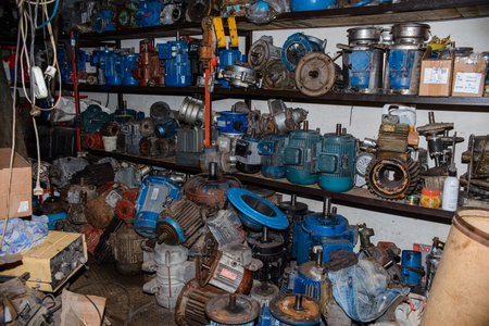 Many broken industrial electric motors in garage on rack. Electrical equipment under repair, dirty asynchronous current generatorsの写真素材
