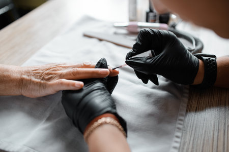 Manicurist paints a woman's nails with varnish. Close-up, selective focus. nail care. beauty salon.の写真素材